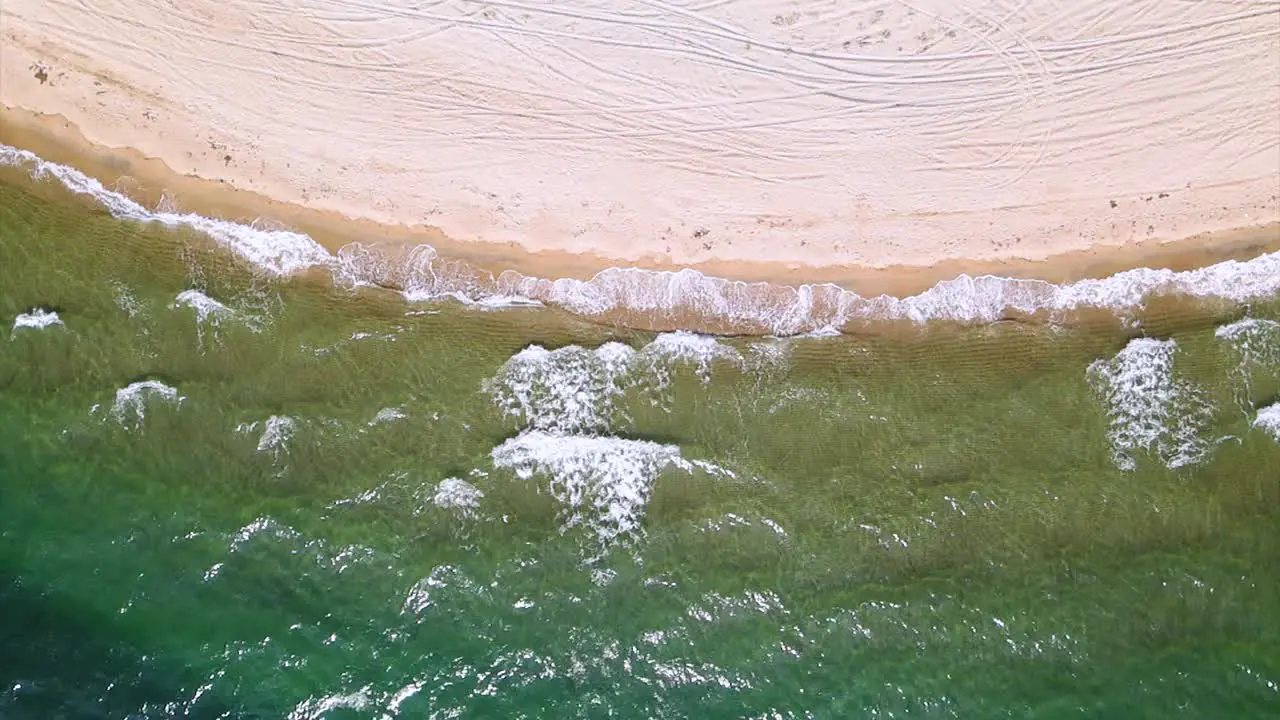 Slow motion overhead drone clip over a beatiful beach with crystal waters and waves crushing on the ground in Keramoti Kavala Northern Greece