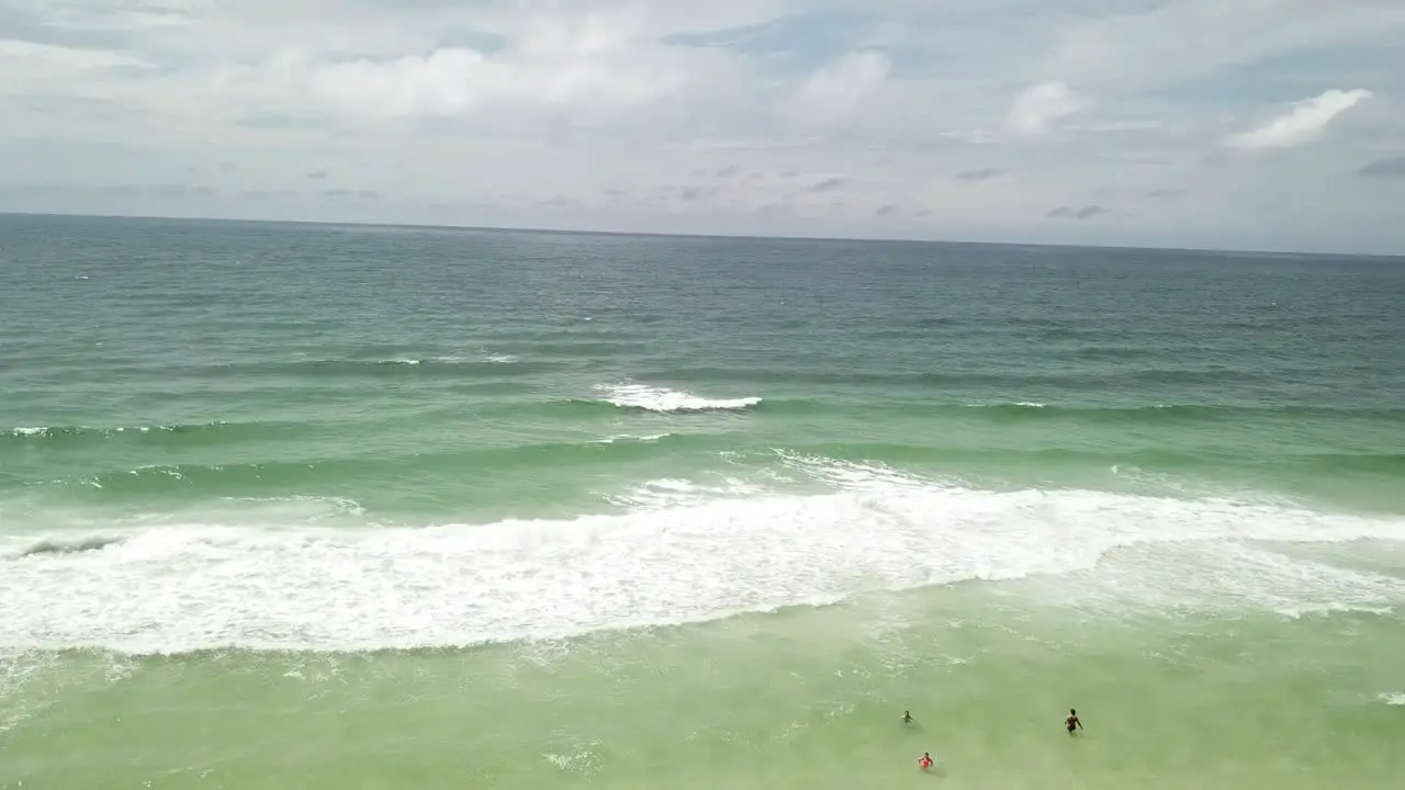 Aerial View Of Beach And Ocean Waves With Tourists Enjoying The Water In Summer drone shot