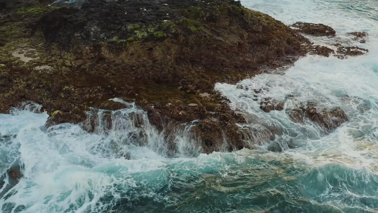 Drone shot of waves bounce on a rock at the beach