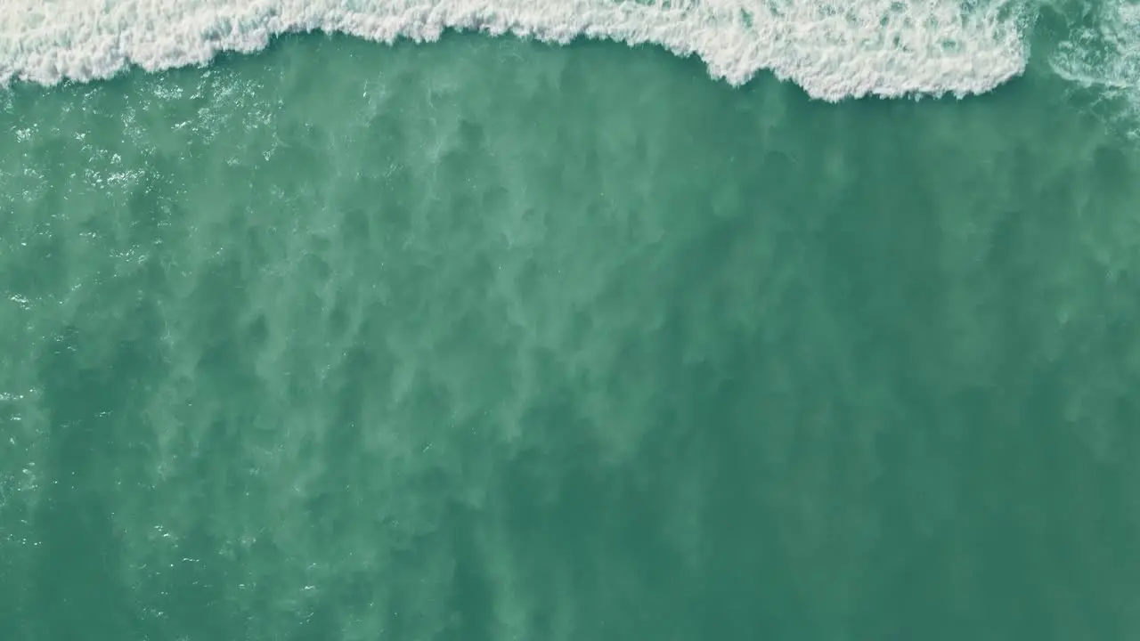 Aerial view going into the ocean with waves crashing