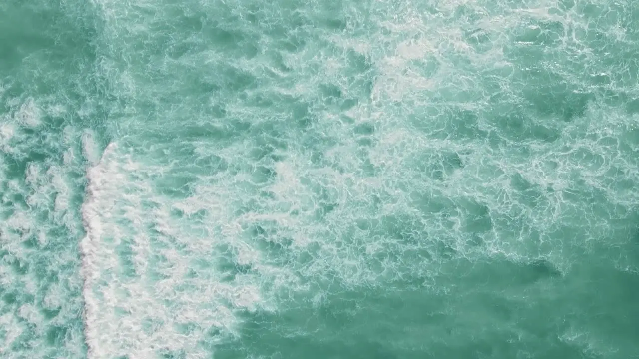 Drone shot going along the ocean with waves breaking