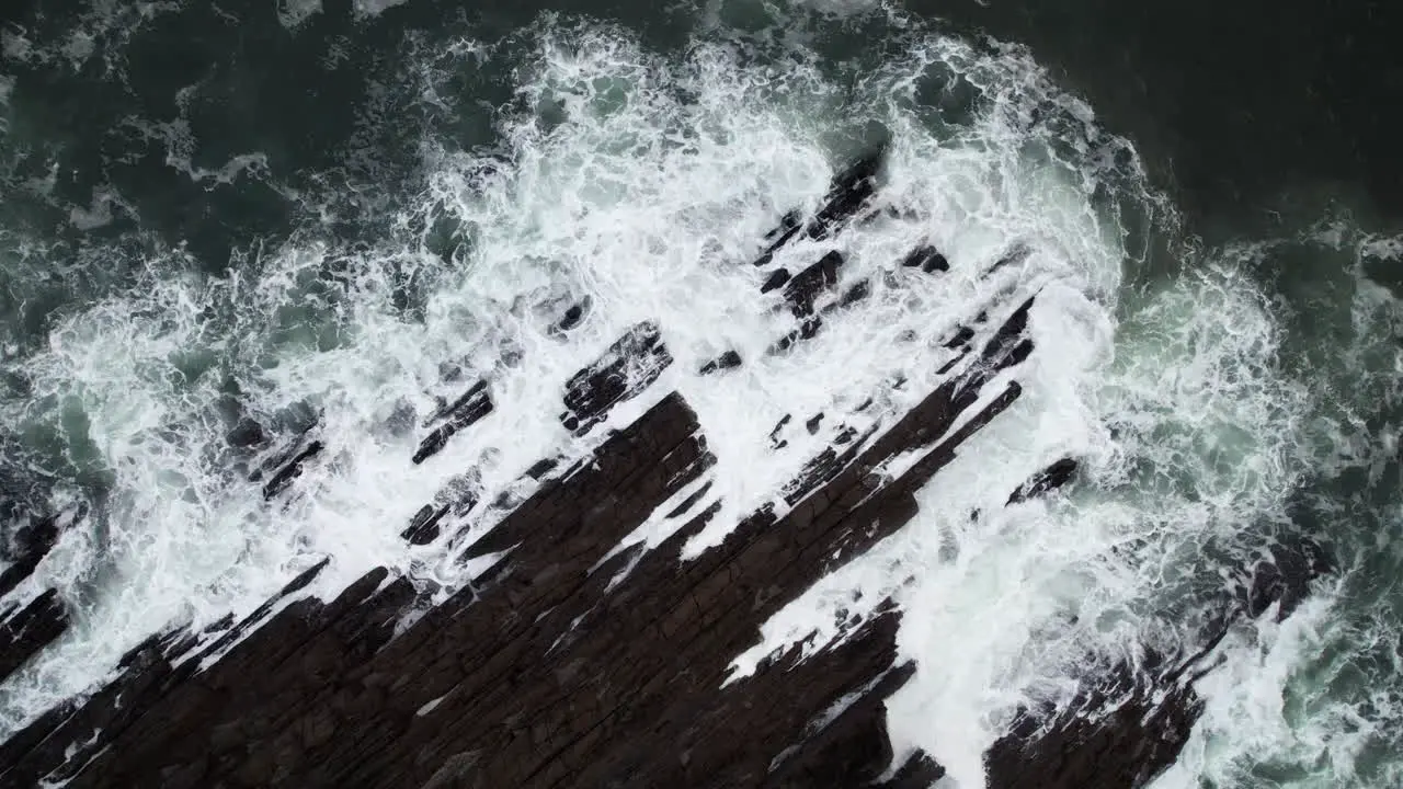 Birdseye Aerial View of Ocean Waves Crushing on Rugged Rocky Coastline on Cold Autumn Day in Ireland Top Down Drone Shot