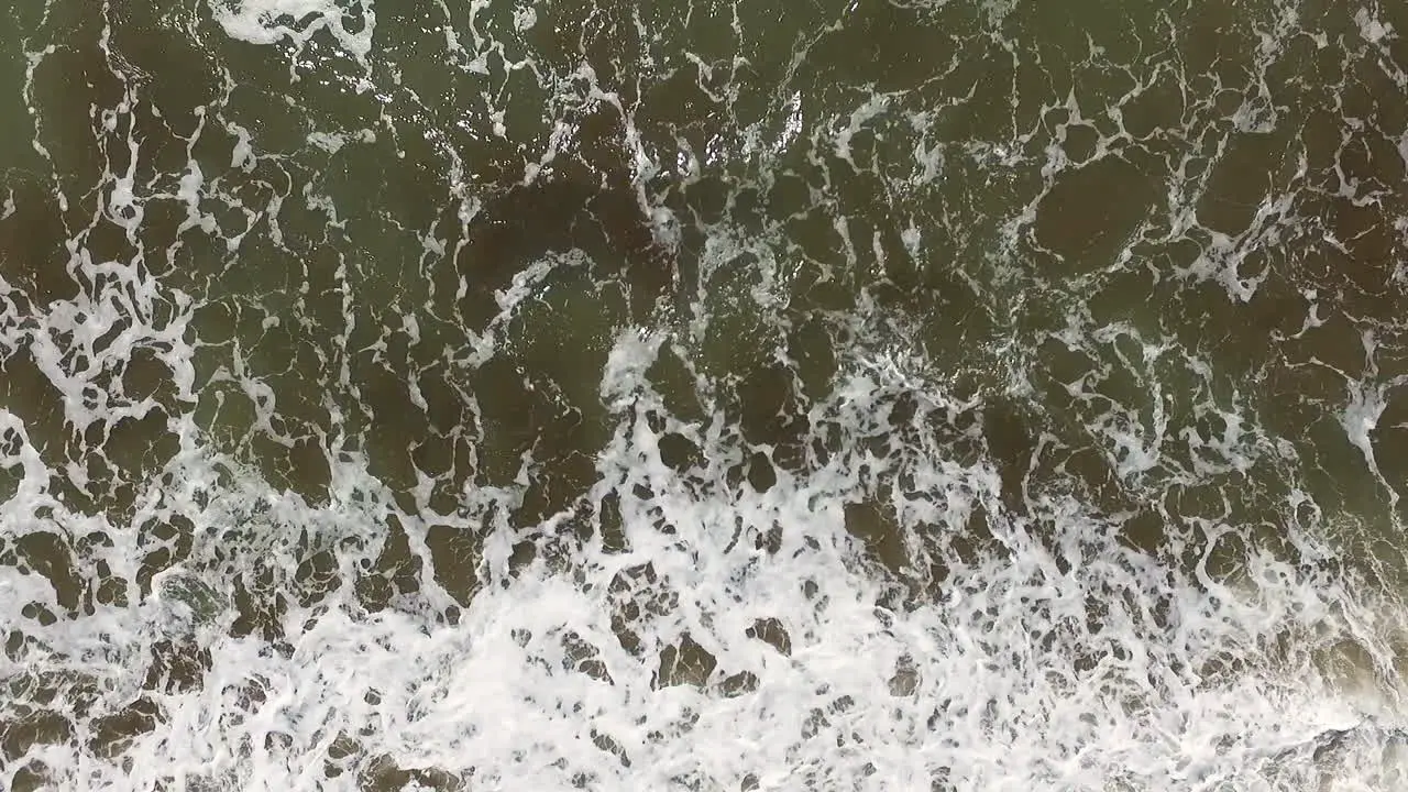 Top Down Aerial View of Ocean Waves Breaking on Sandy Beach on Sunny Day