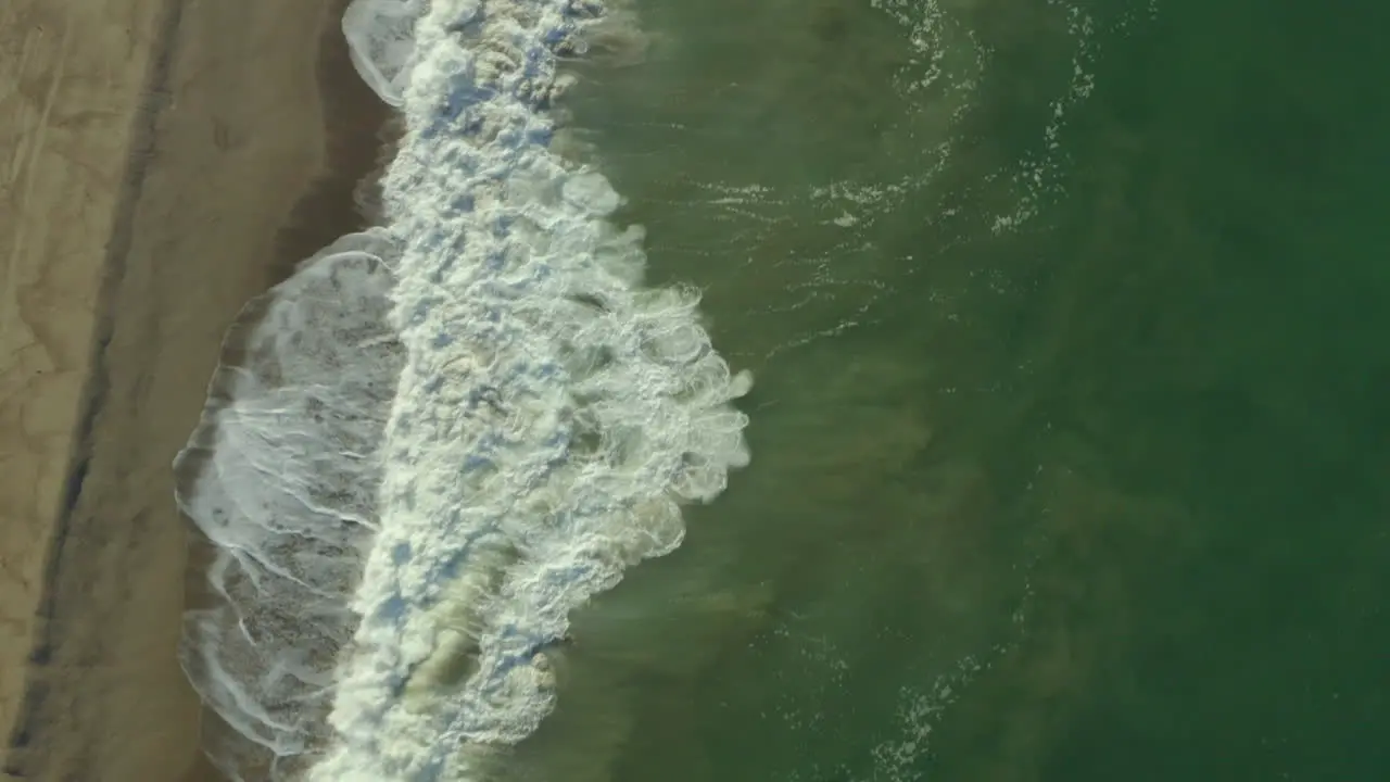 Dolly shot along a beach with waves crashing on the shoreline