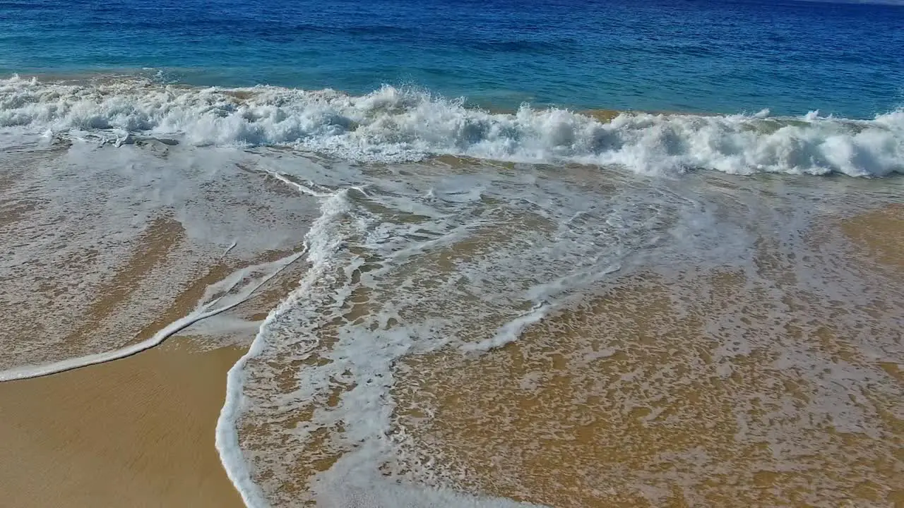 Panning waves crashing on sandy beach in Maui Hawaii with beautiful sky and water