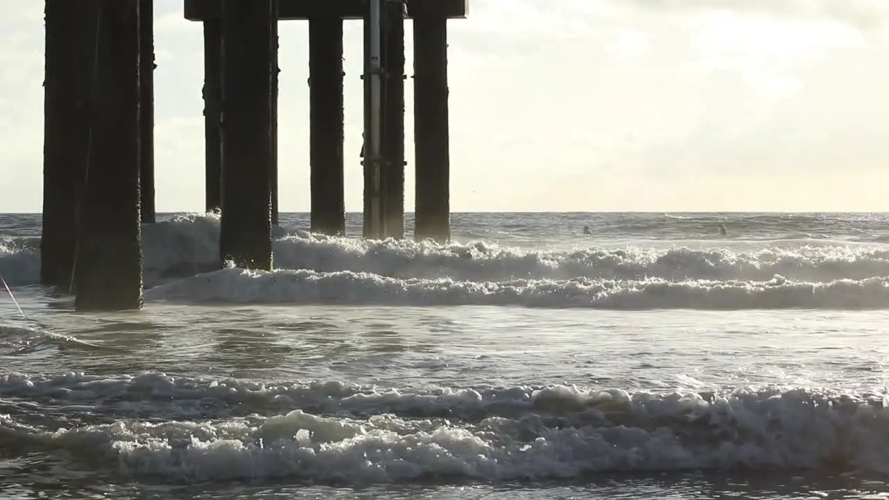 Waves crashing on a pier in slow motion during sunrise