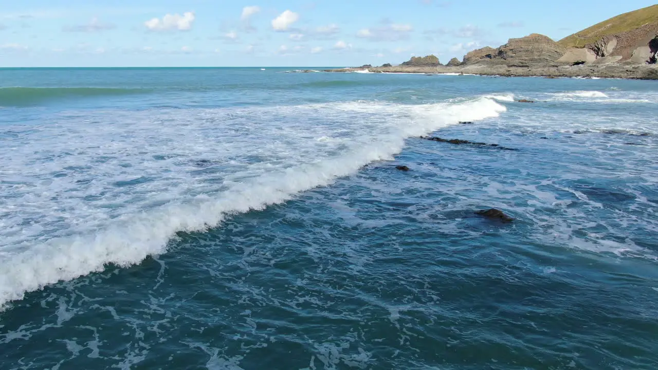 Aerial shot over the waves in the sea at Spekes Mill coastal beach in Devon