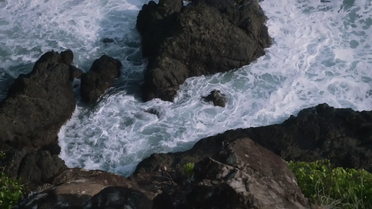 Looking down on the waves crashing into the rocky tropical shoreline in Costa Rica