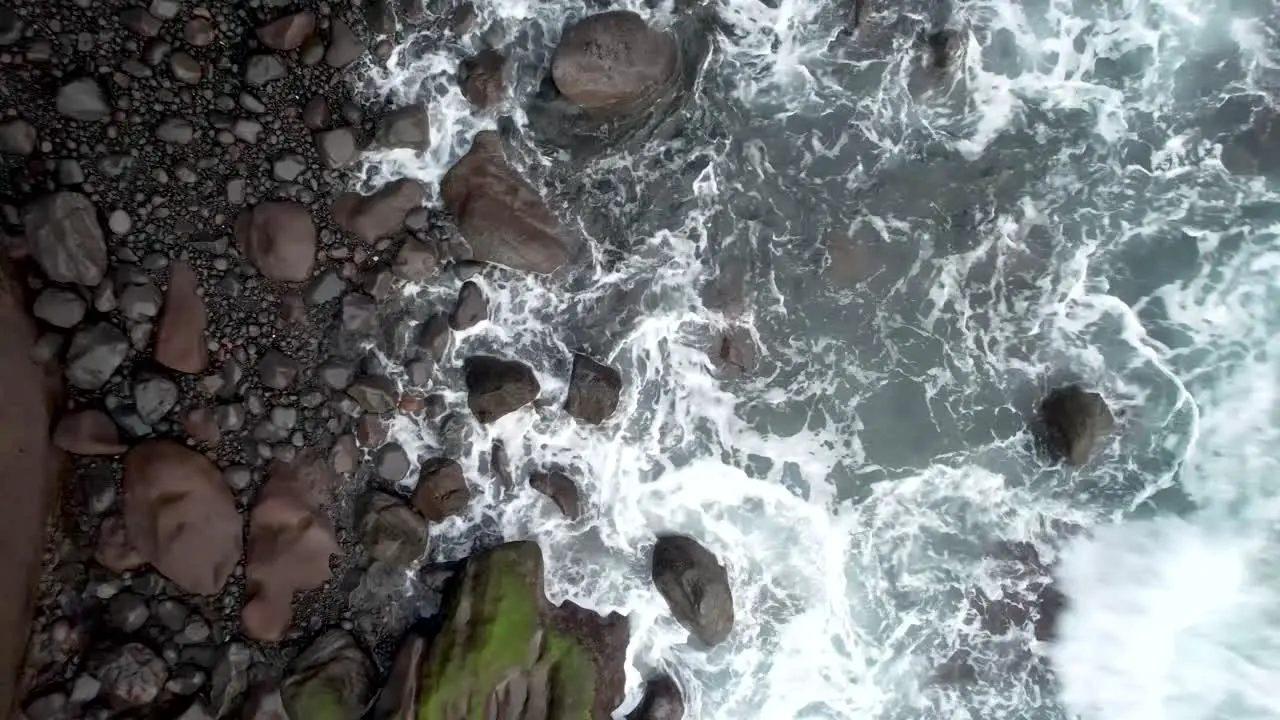 Aerial of the ocean waves washing up on rocks in black sand beach in El Zonte beach  La Libertad El Salvador