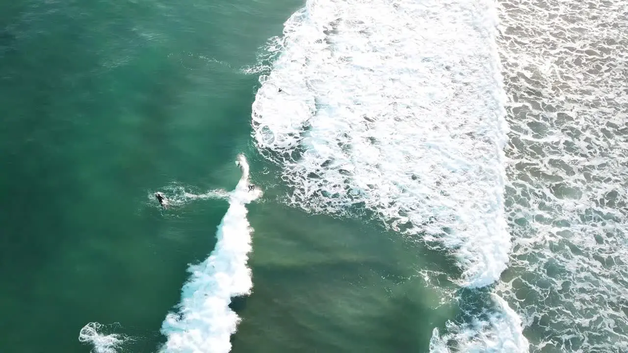 Drone aerial of surfer catching wave on blue water on Great Ocean Road on a sunny summer day