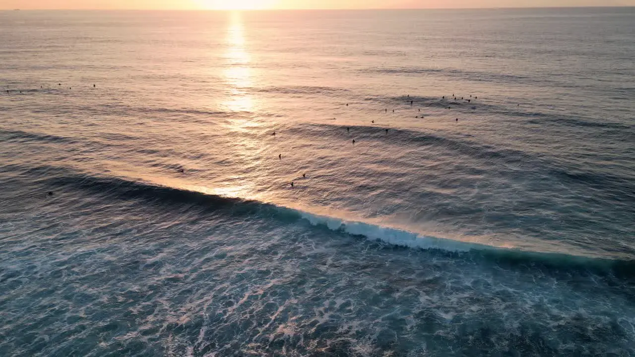 Aerial view of some surfers waiting for the waves at sunset