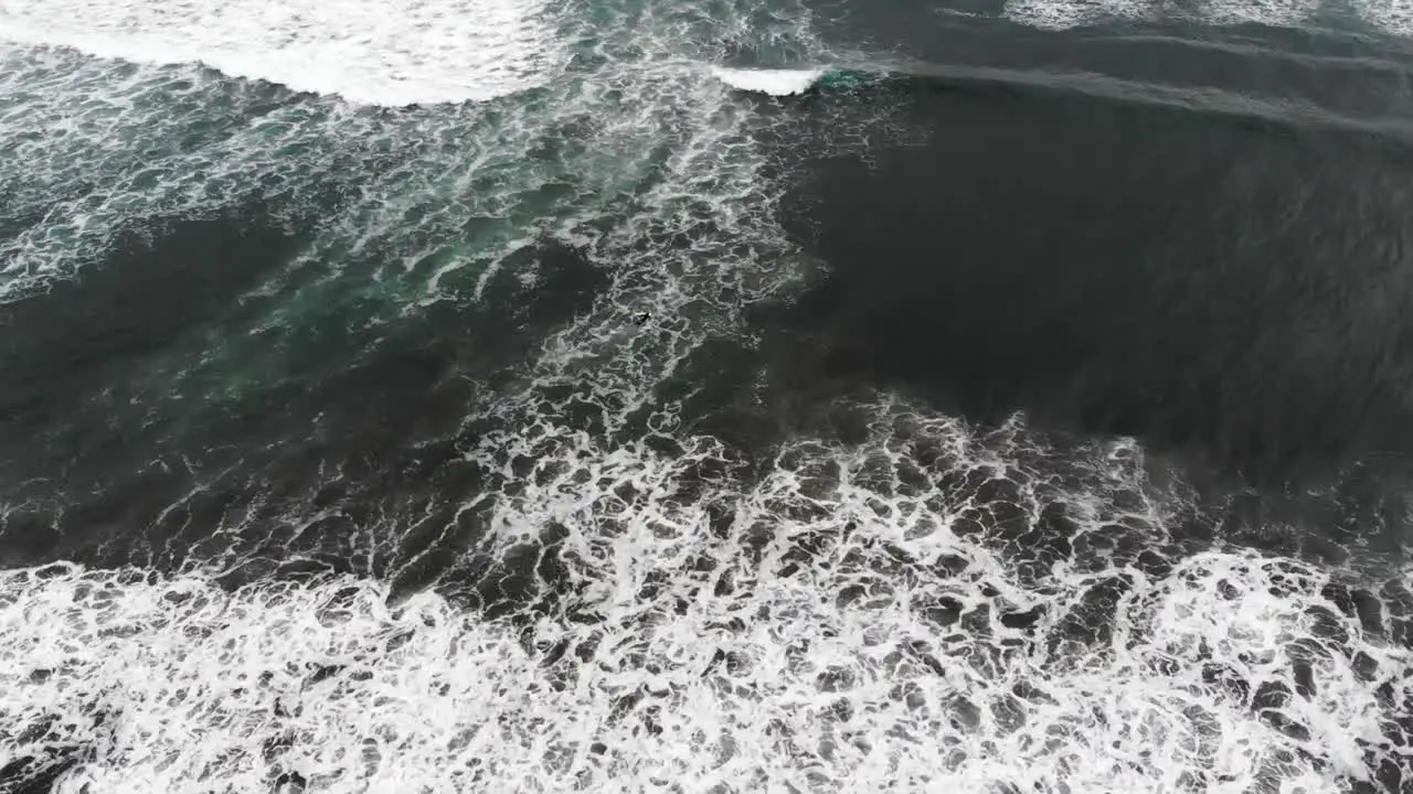 drone flying over crashing waves tilting up and pulling back