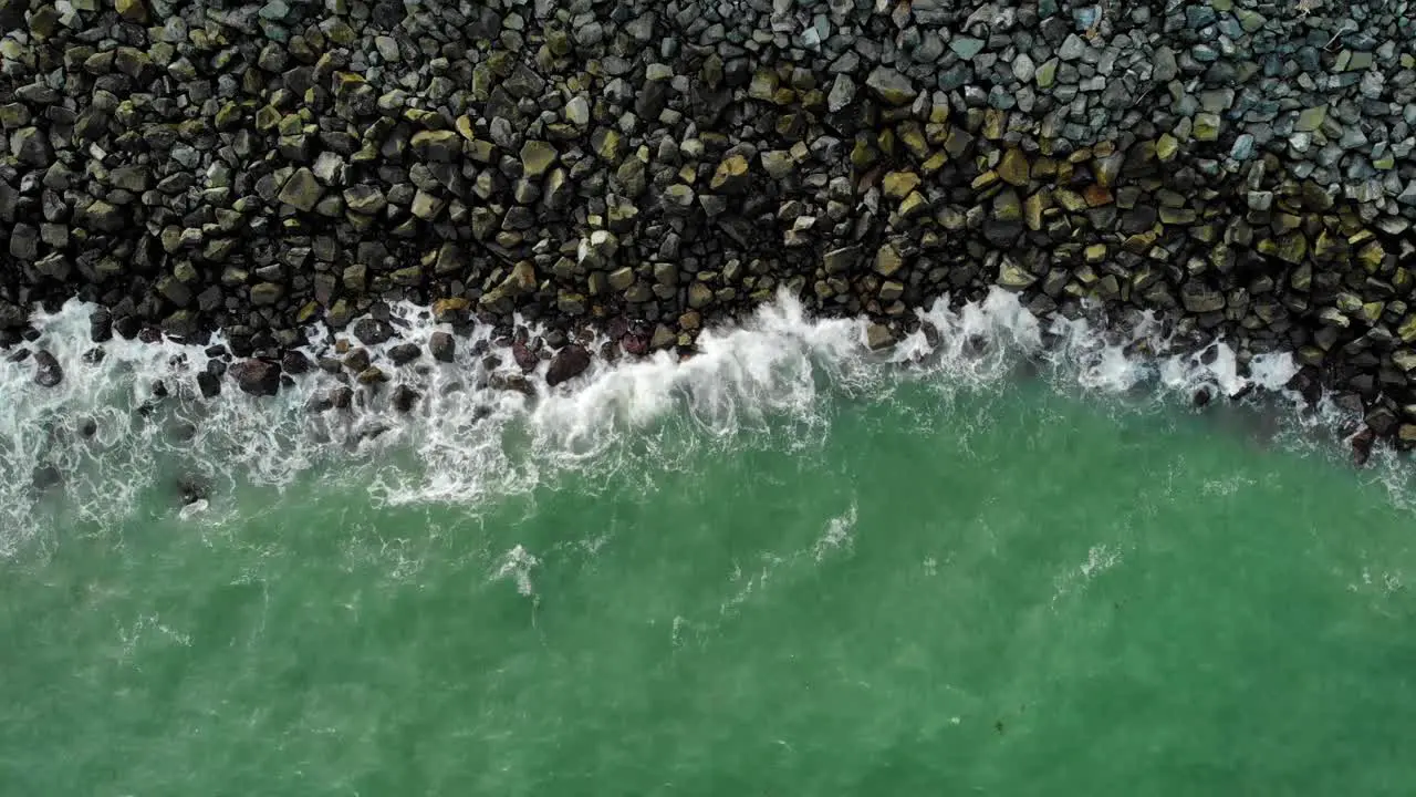 Aerial view above turquoise waves washing over a rocky coast in Mackay Australia top down drone shot