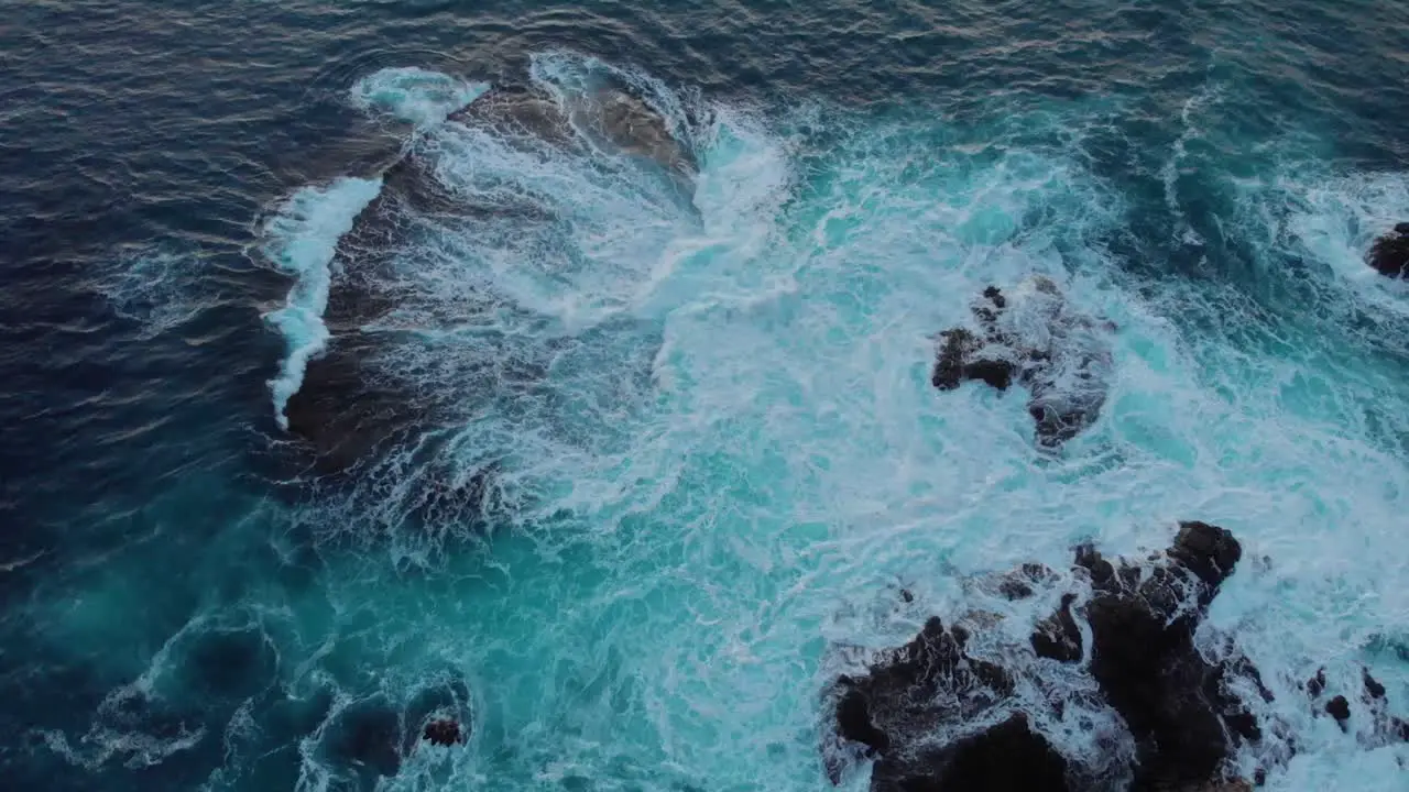 Birds eye drone shot over tropical crashing waves at dusk