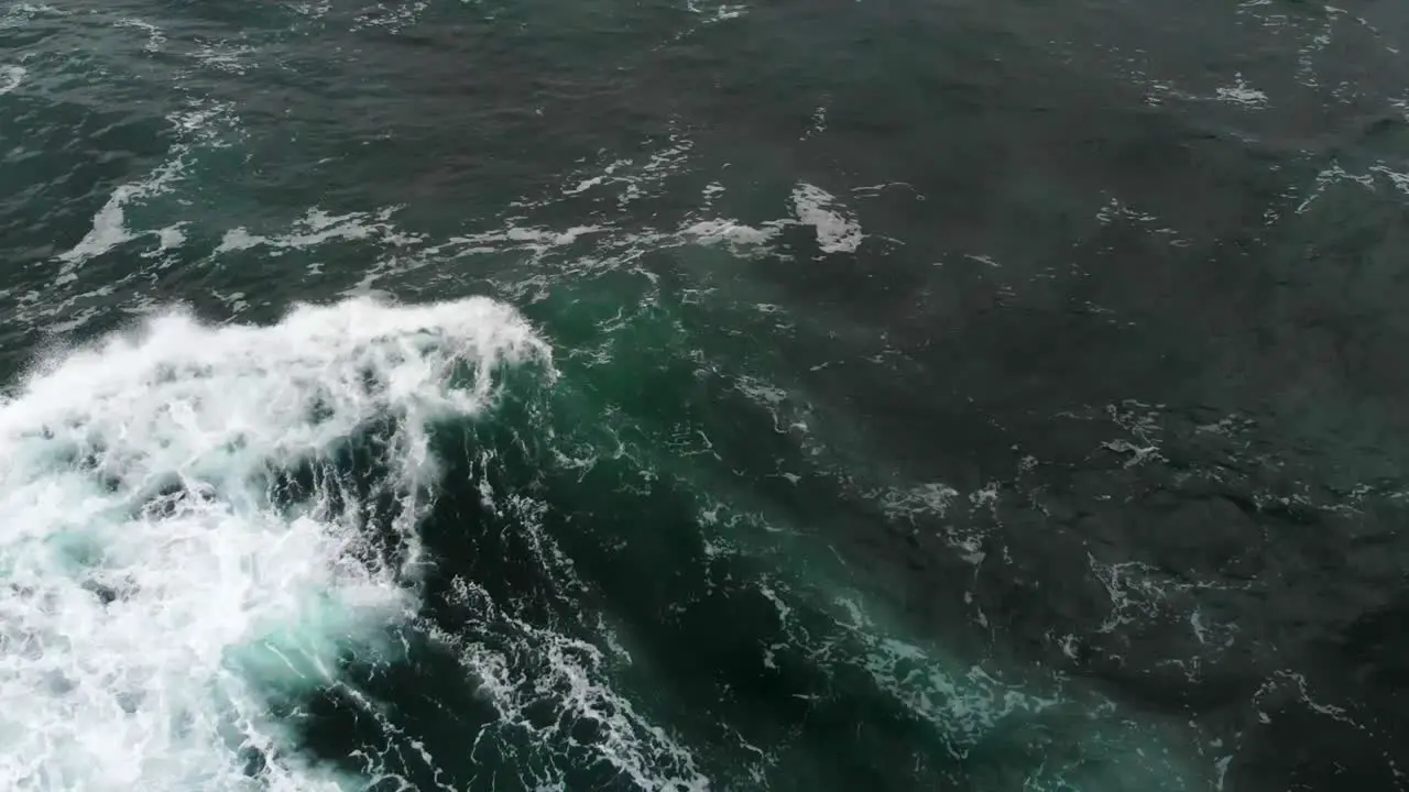 Drone flying over surfer paddling out to catch a wave in the ocean