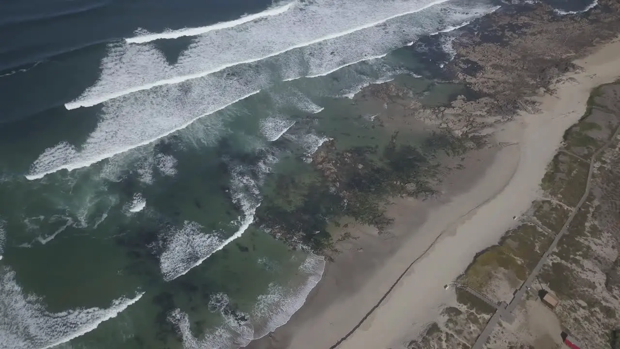 Aerial shot of a beach being washed off by the waves of a sea