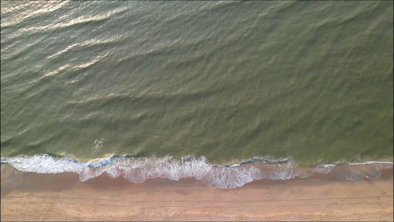 Top down aerial view of sea waves washing up on beach