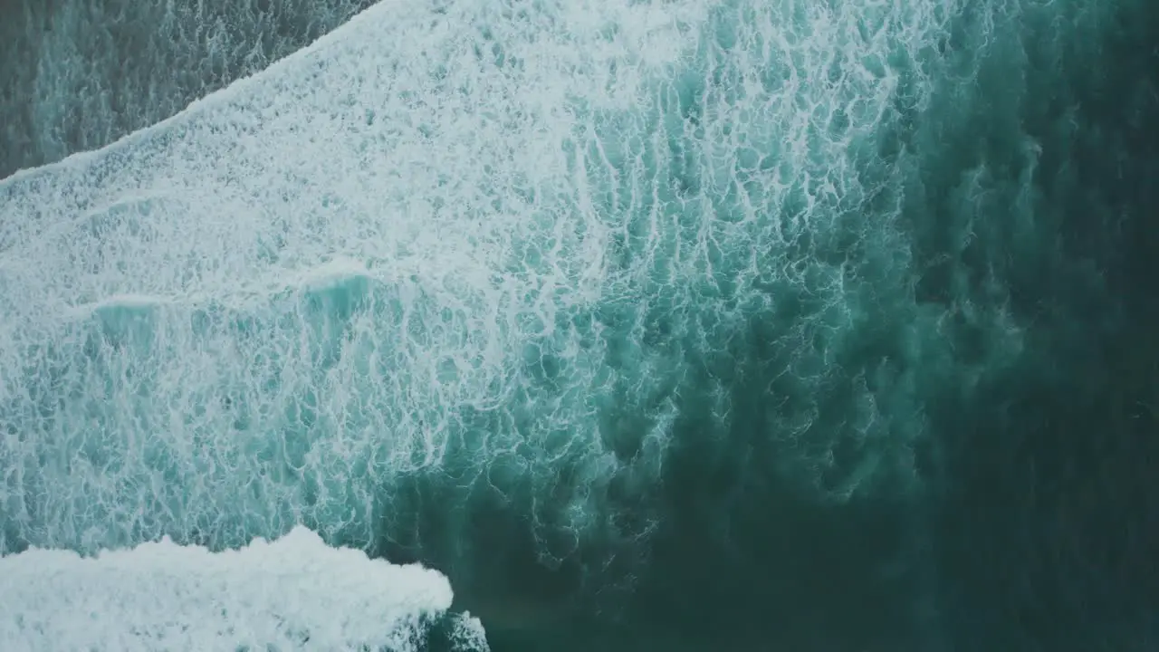 Aerial view of deep blue white cap waves crashing on shore in Kauai Hawaii