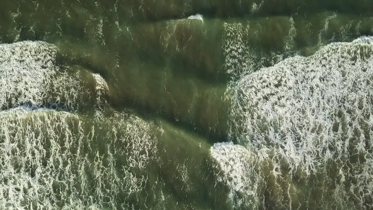 Bird's eye view of sea waves reaching a beach resort with tourist