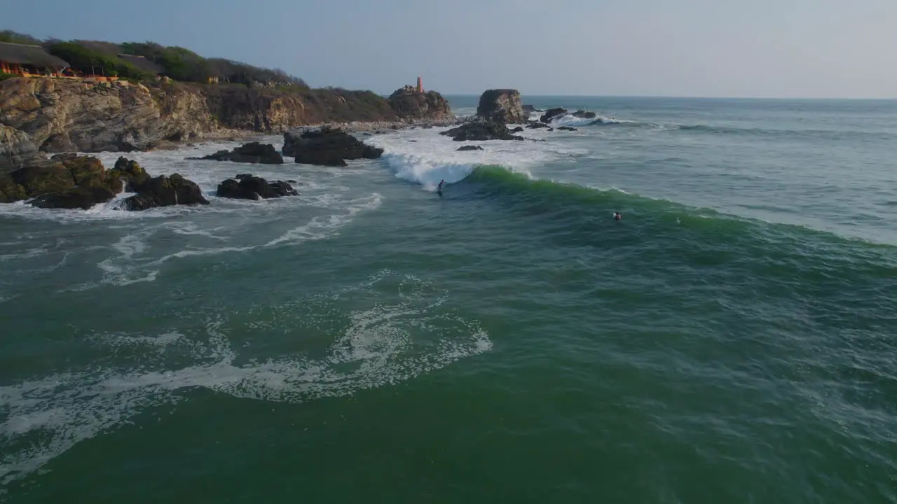 Aerial tracking shot of a surfer catching a wave completing turns and then falling