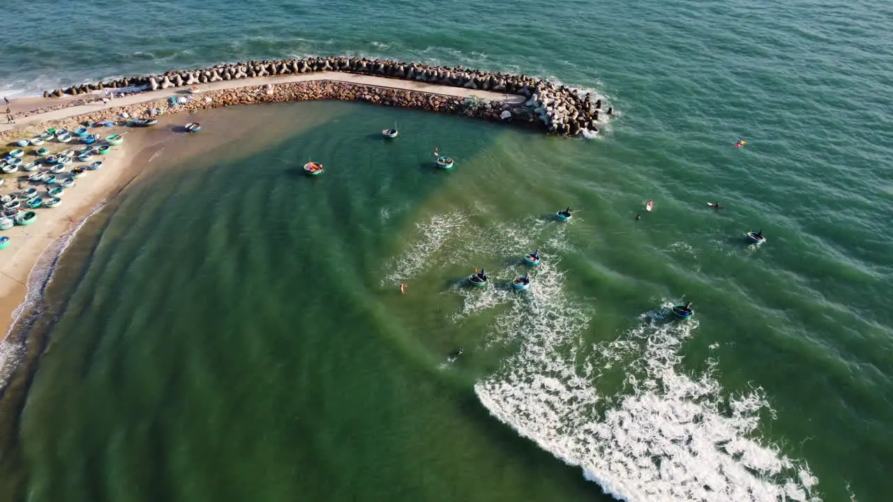 Aerial people rowing out Vietnamese round coracle boats out from beach shore