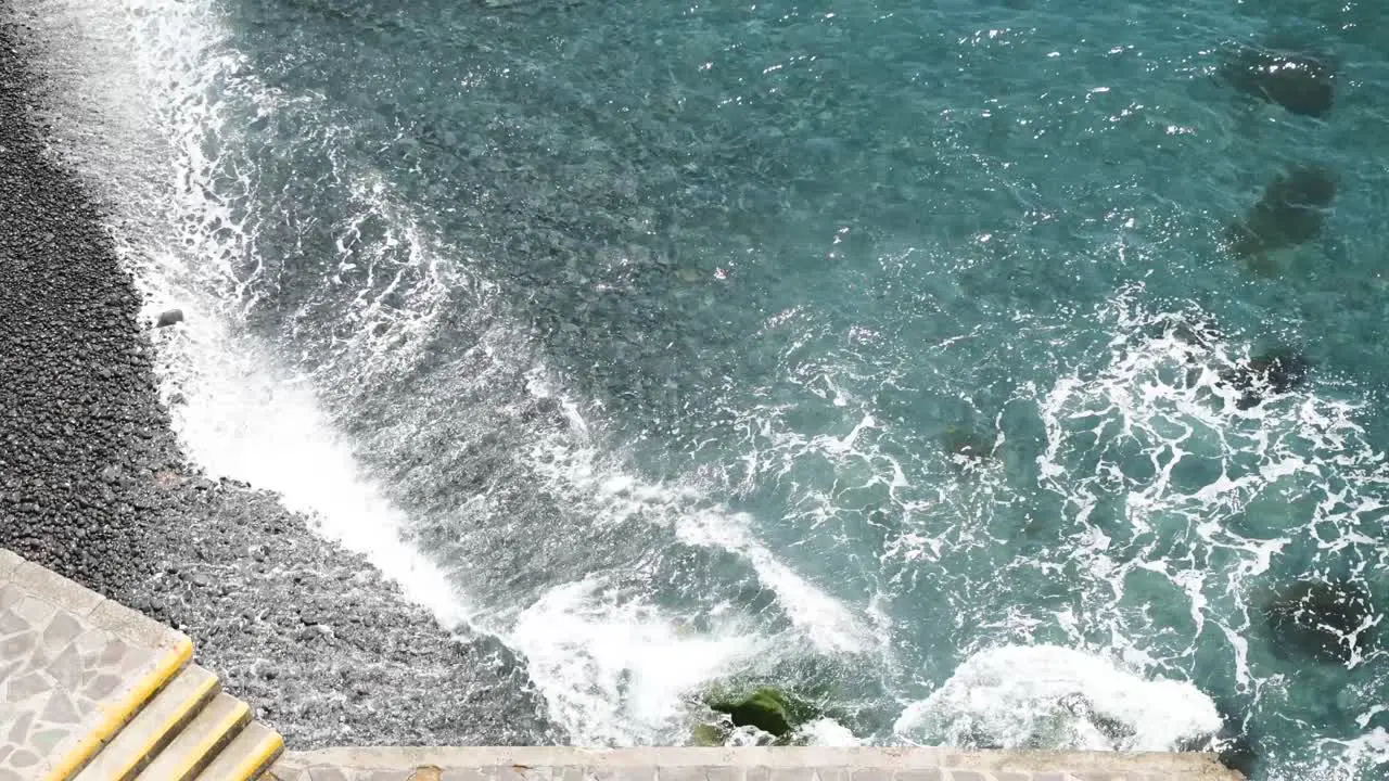 Above shot of crashing waves on a black stone beach