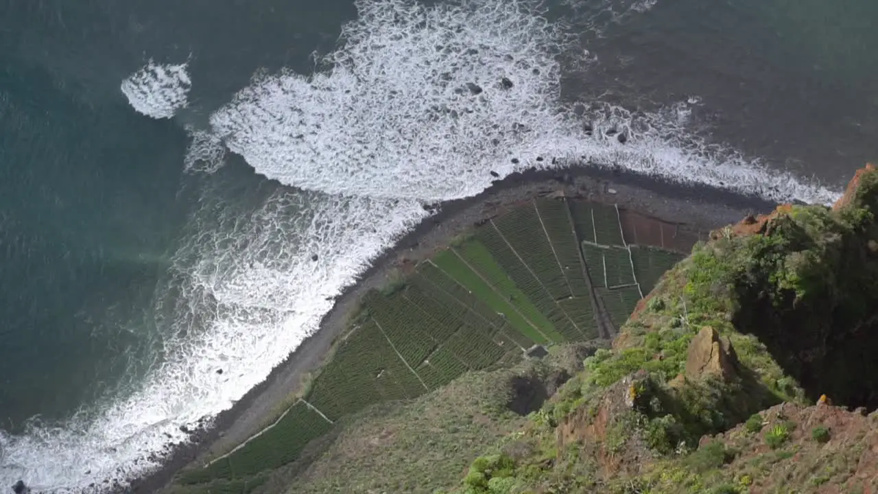 Top view of a beautiful black sand beach with some crop fields at shore