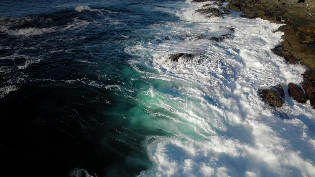 aerial shot of ocean waves hitting rocky shore crashing violently