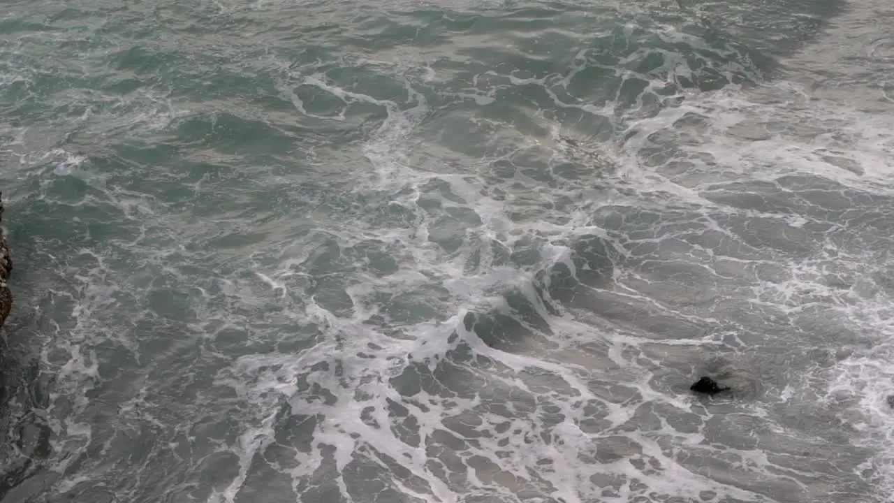 High above view down towards rough sea with waves breaking against rocks