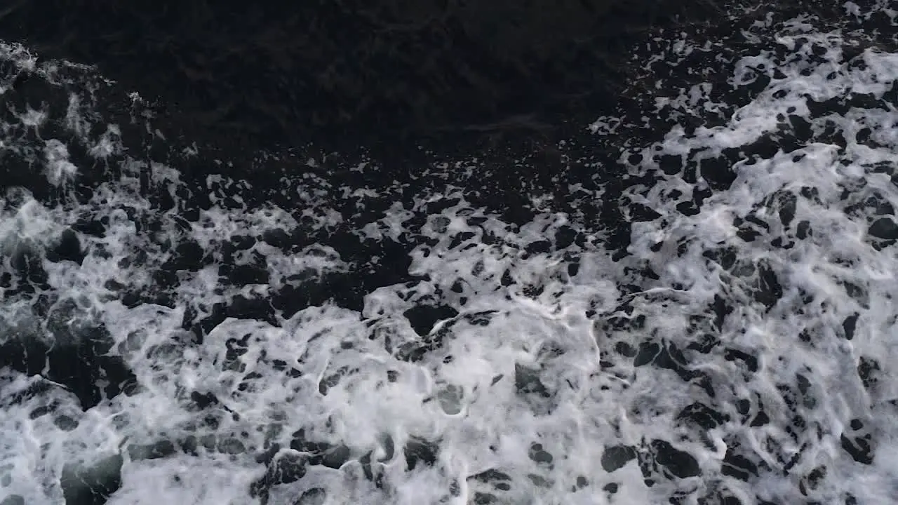 Waves created by a moving ship with white foam rising up in a dark deep sea