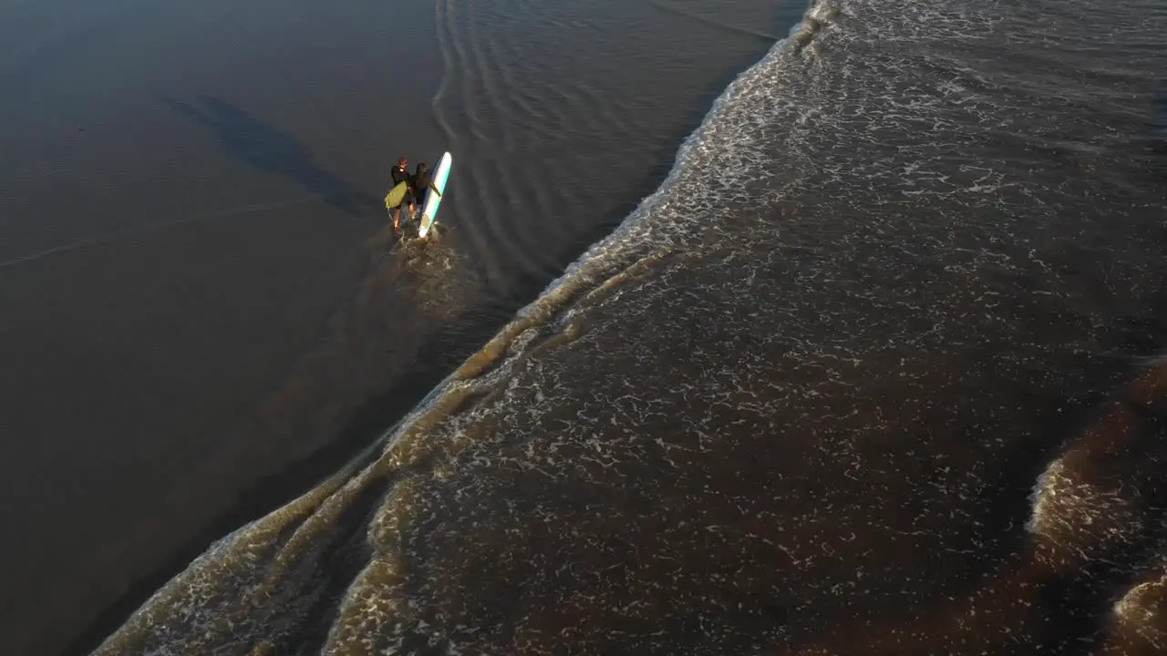 Surfers Walking Along Shoreline