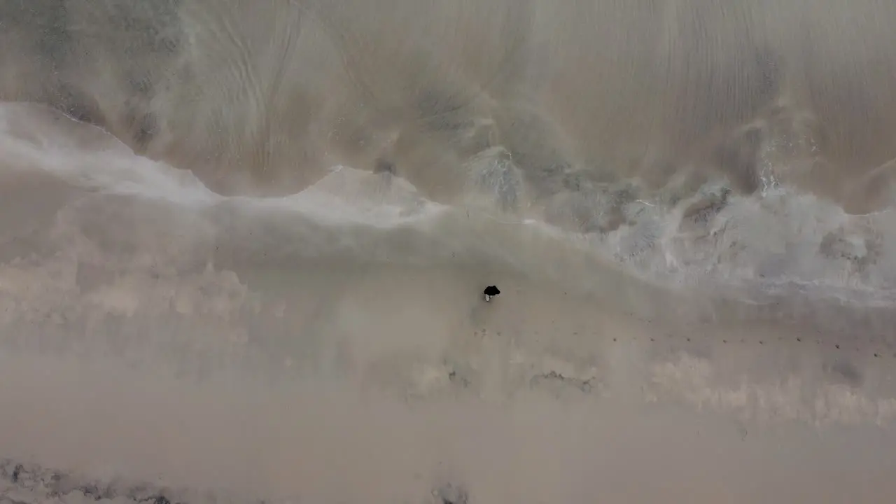 Flying at a beach in Norway looking down at a person standing at the water