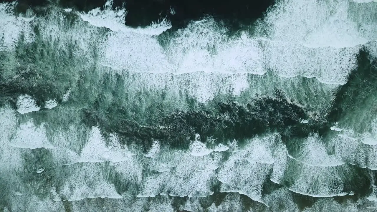 Overhead aerial of multiple waves crashing on a beach