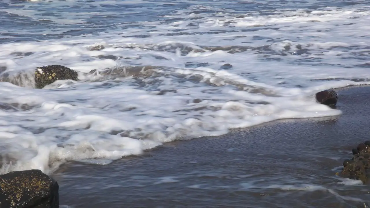 close-up of waves on a rocky beach during the day