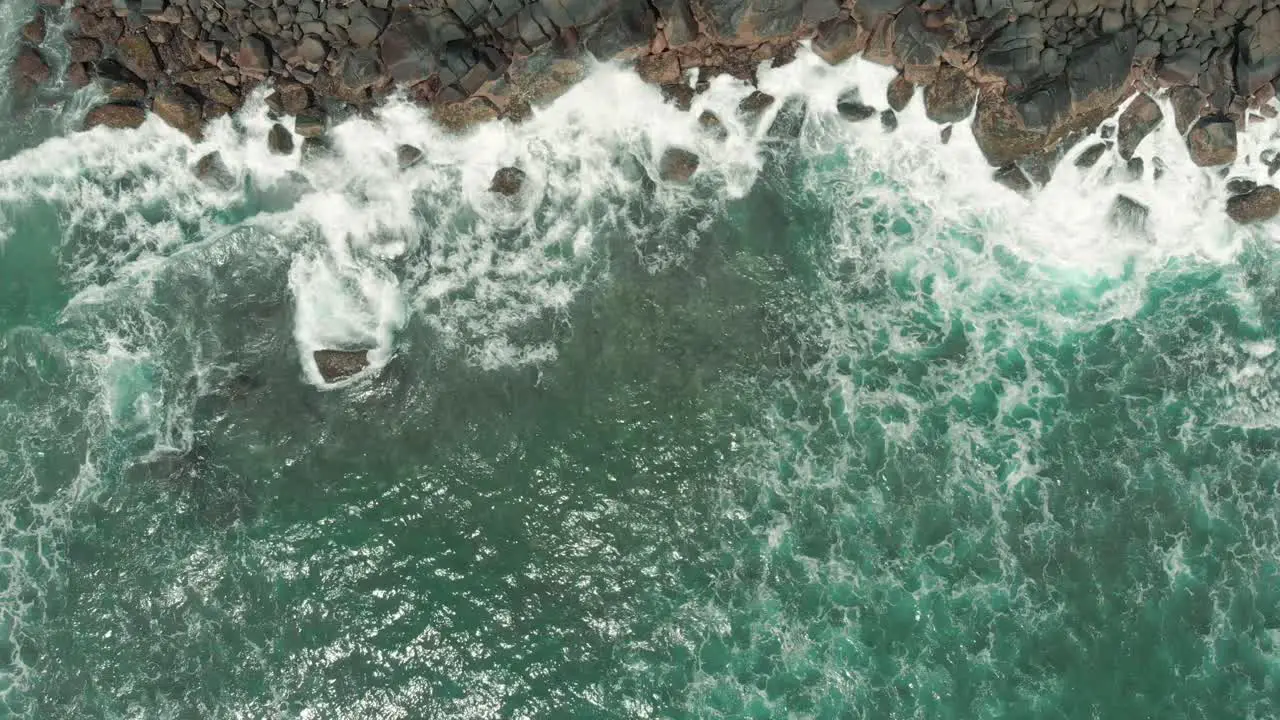 Aerial drone view of waves crashing against the rocks on a beach