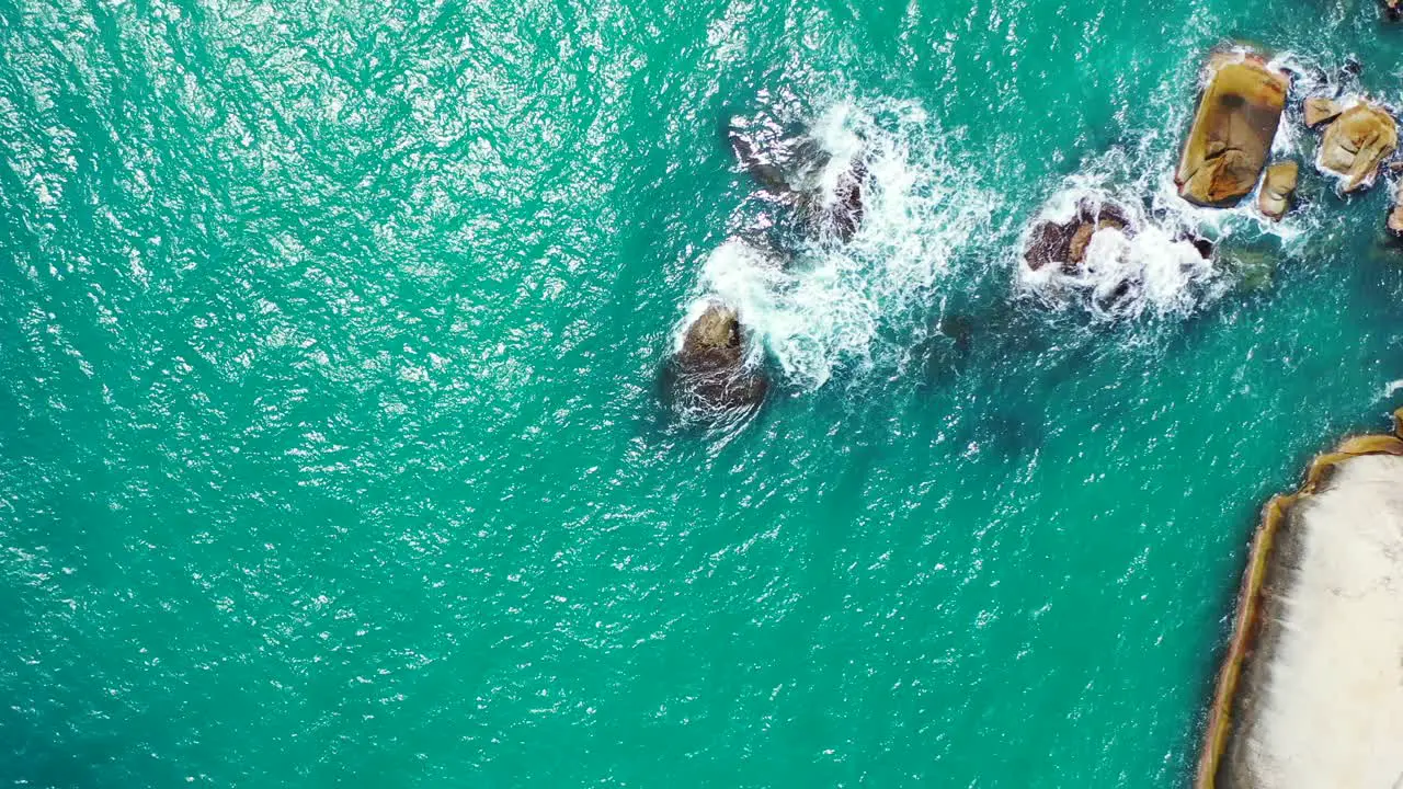 foamy waves crashing on the boulders in the emerald sea