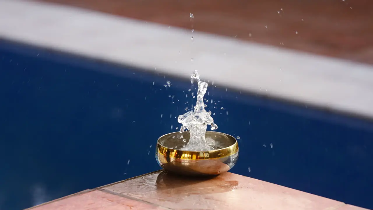 water falling fast and splashing in a small golden bowl in slow motion creating a mesmerizing and tranquil scene