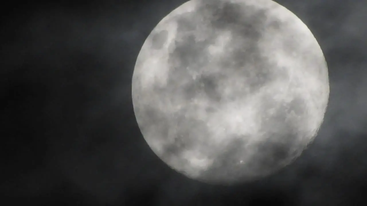 Haunted full moon with eerie dark clouds moving past in the foreground perfect for halloween or scary video transitions