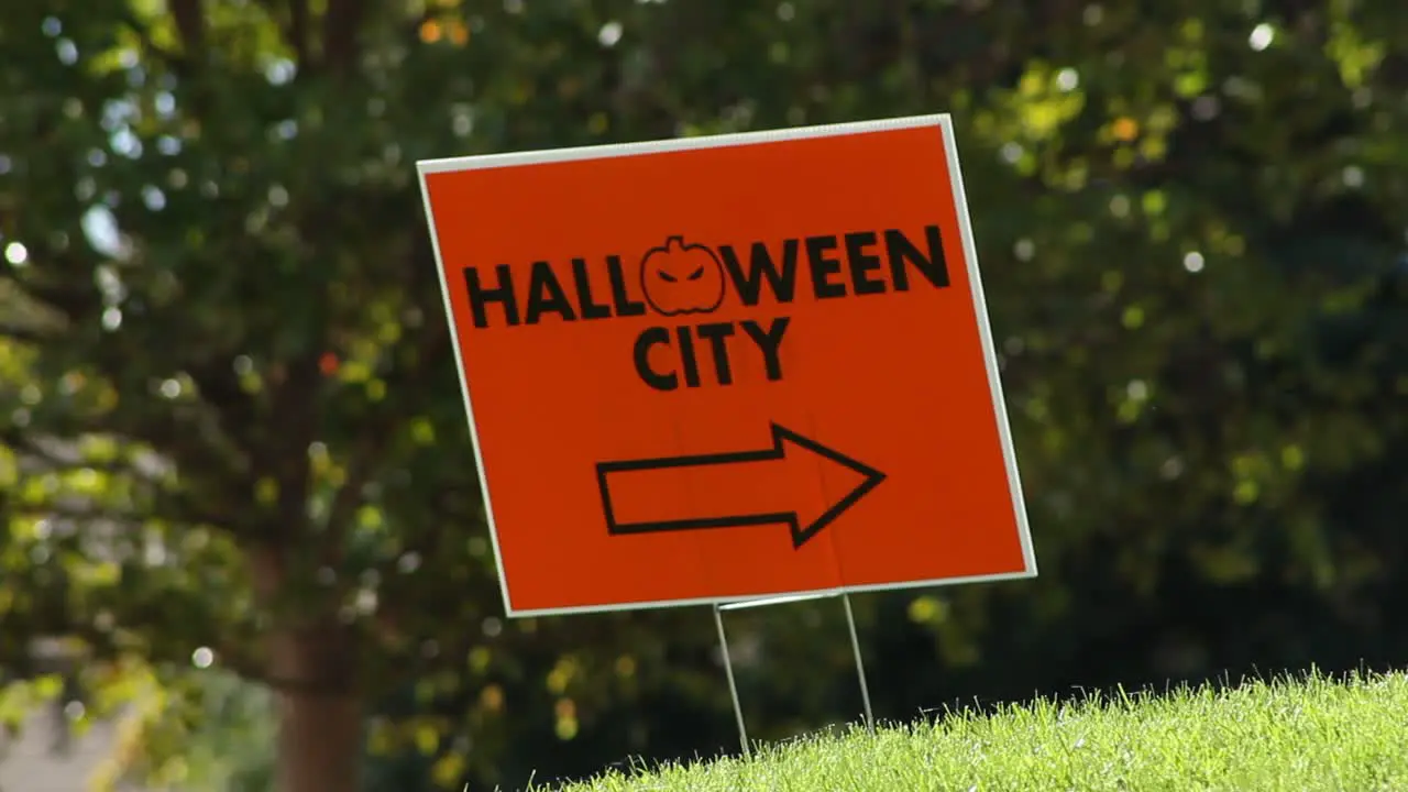 Halloween City Sign Blowing in the Wind Cars in Background