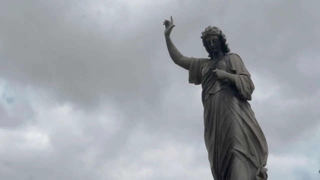 Cemetary statue with a timelapsed background of clouds and sky