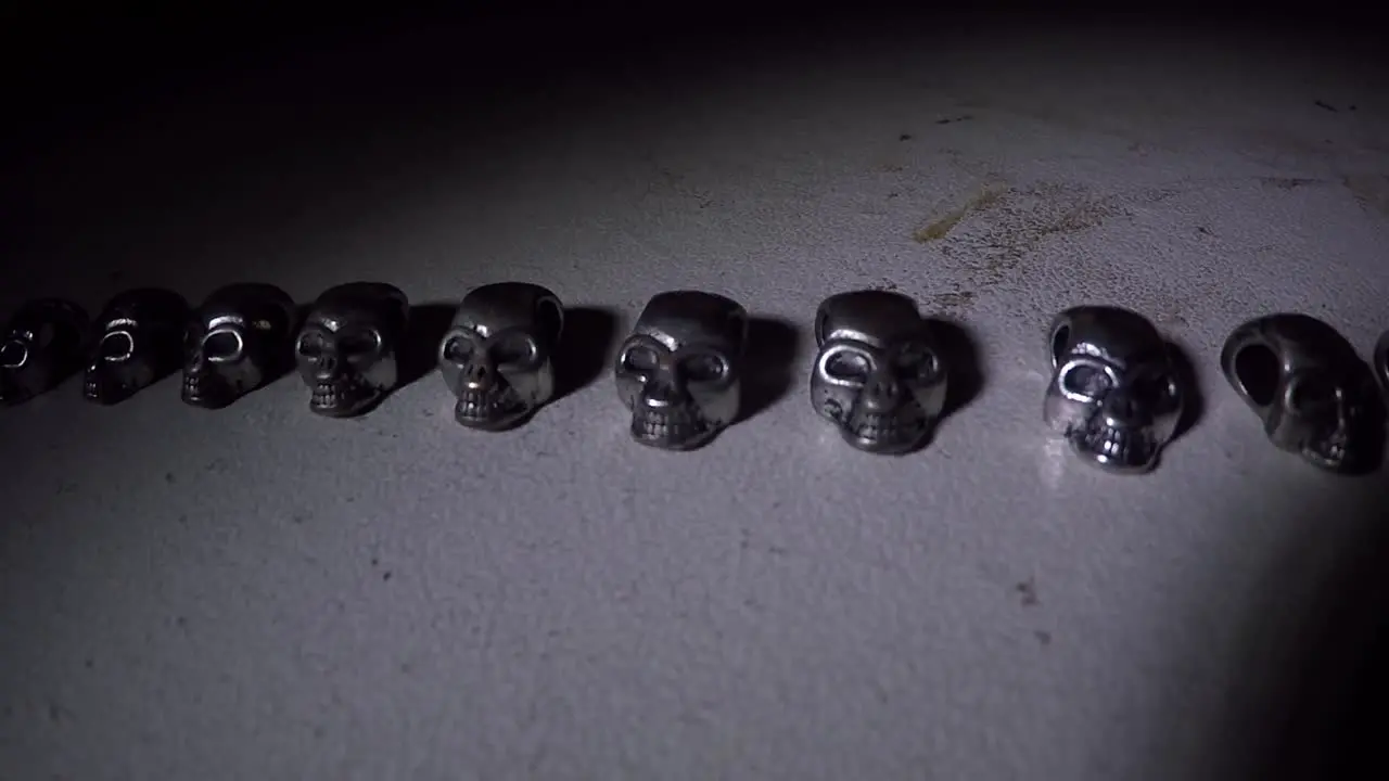 Mini silver skulls on a table in the dark