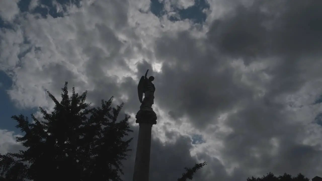 Timelapse of sun-moon passing behind cemetary statue on pillar