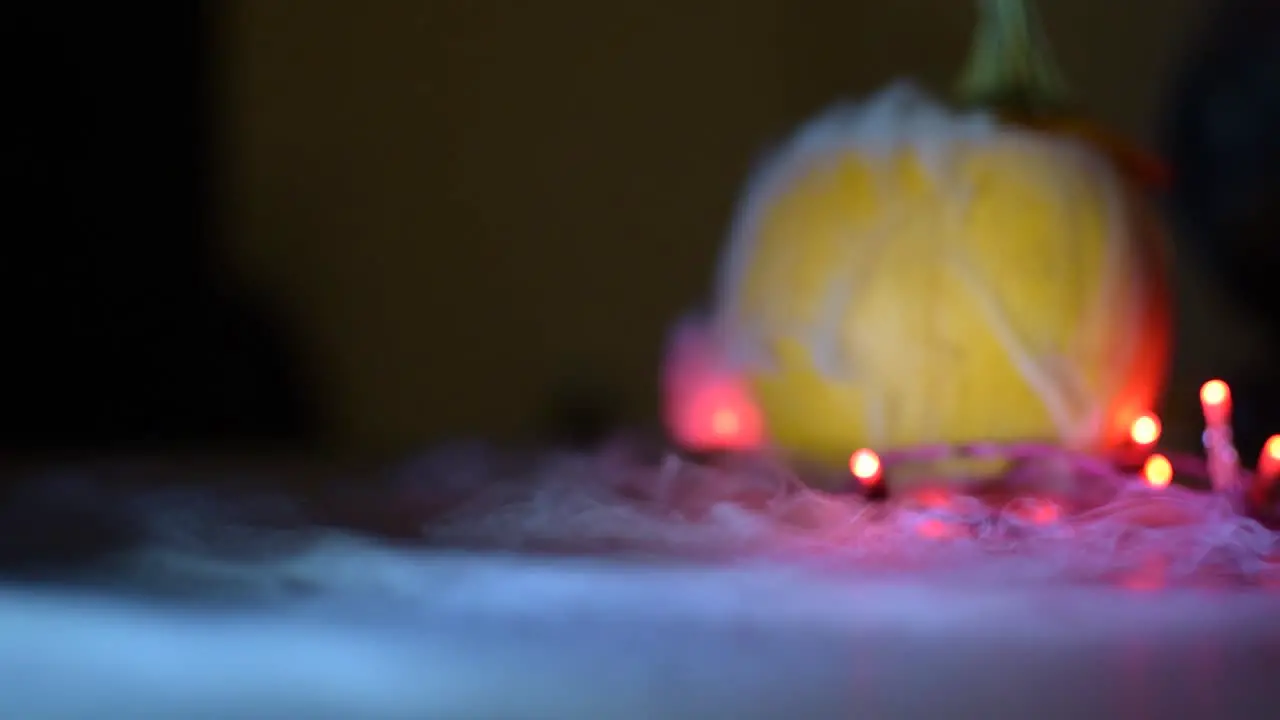 dry ice mist fog flowing from a pumpkin onto a flat surface lights around the pumpkin