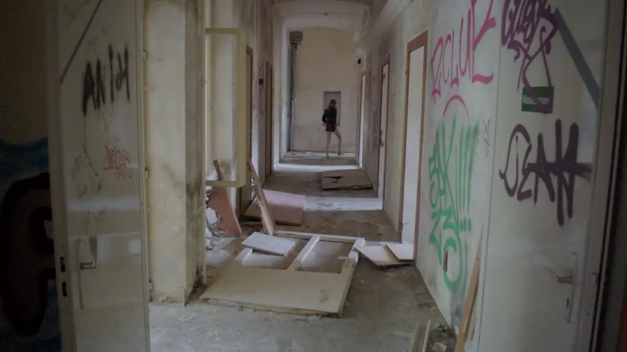 Long Corridor in an abandoned Building with a Girl walking at the end of it in Slow-Motion