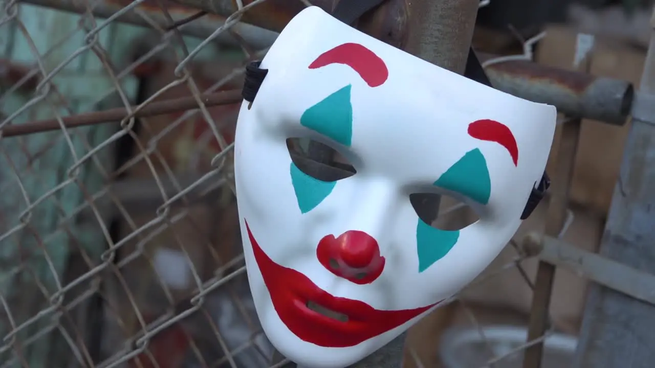 The Joker Themed Clown Mask Hanging From a Chain Link Fence