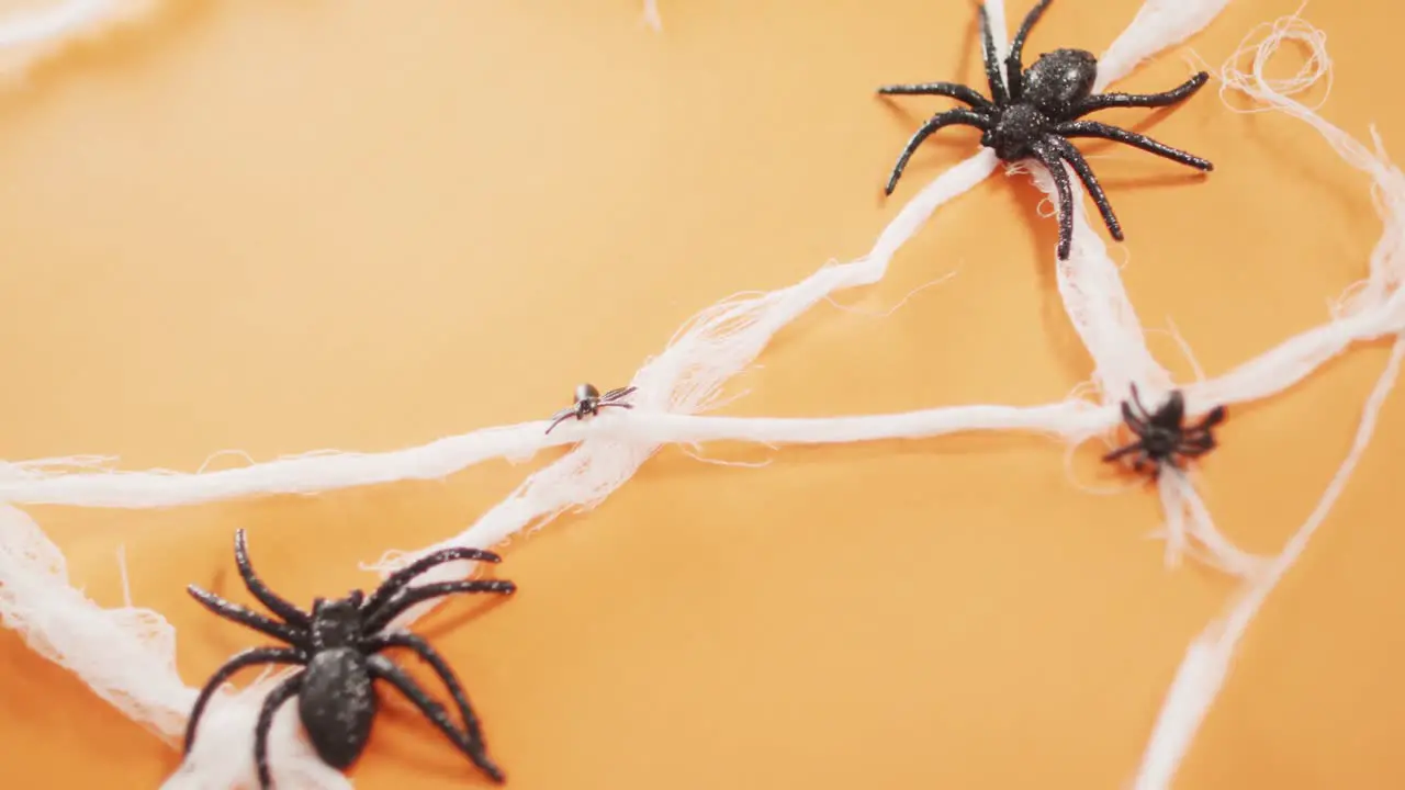 Close up of multiple spider toys forming a spider web against orange background