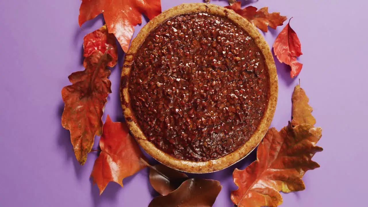 Video of autumn leaves and pie on purple background