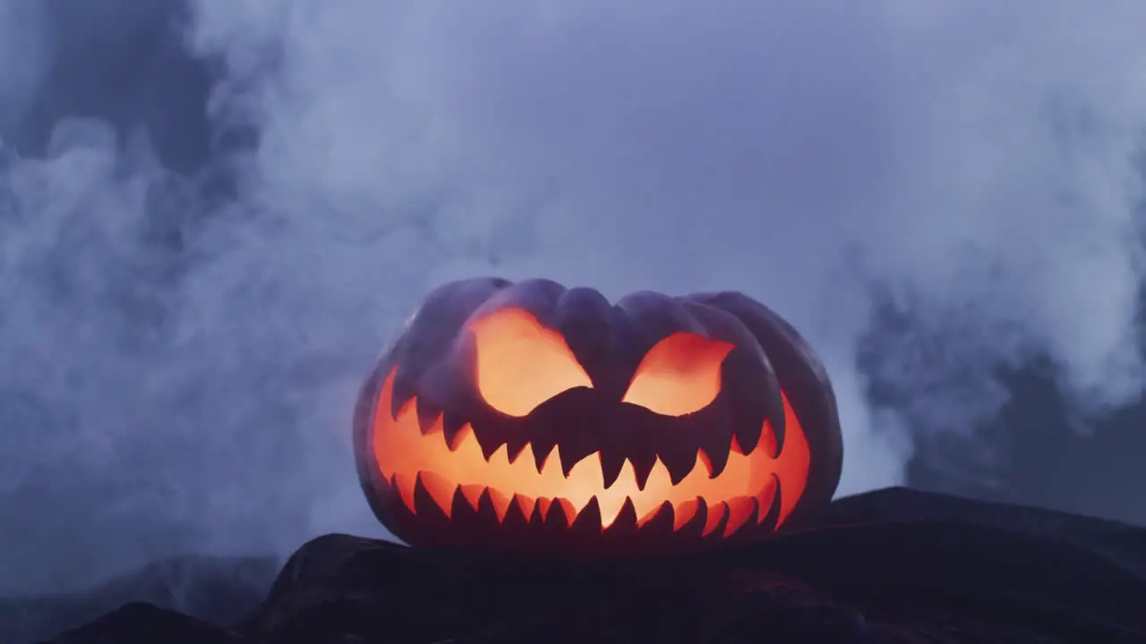 Video of halloween carved pumpkin with smoke on black background