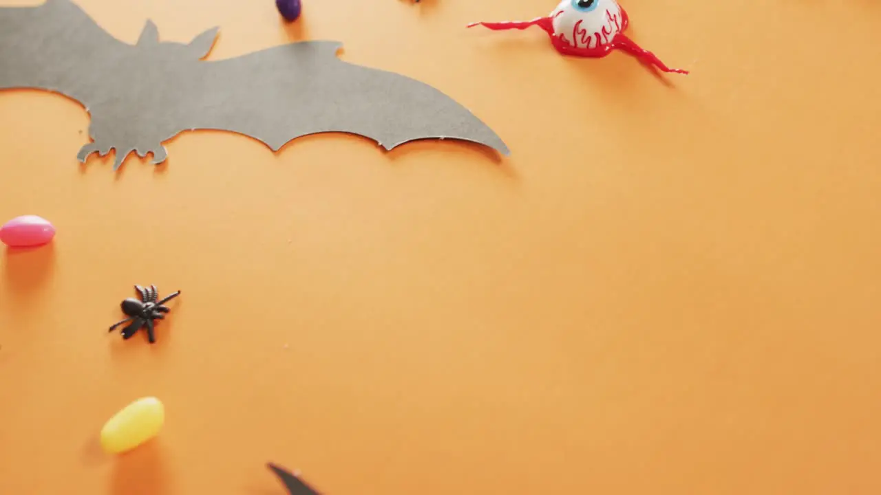 Close up of multiple halloween candies and toys against orange background