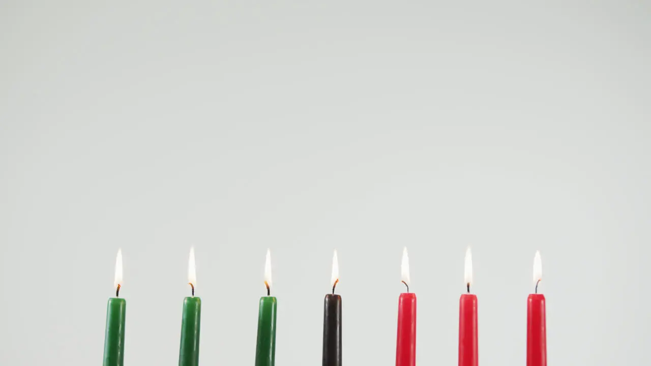 Multiple colorful burning candles and two pumpkins against grey background